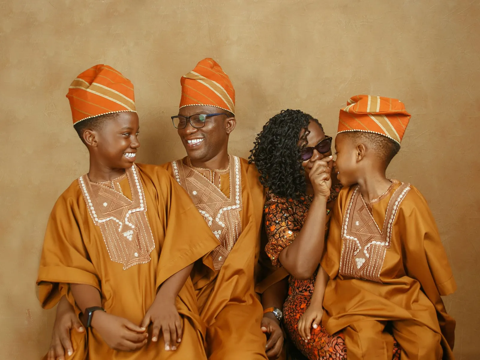 Laughing Nigerian family of four in matching orange traditional outfits